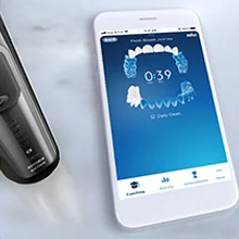 Oral-B iO Zahnbürste neben einem Smartphone, das die Positionserkennung und das Coaching während des Zähneputzens anzeigt.