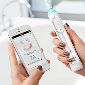 Oral-B iO Zahnbürste, die mit einer Smartphone-App verbunden ist, die eine personalisierte Putzanleitung mit Echtzeit-Feedback anzeigt.