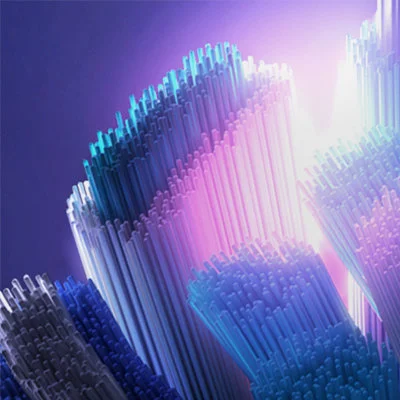 Close-up abstract image of many clustered, thin cylindrical shapes illuminated by light, showing colors from white to blue and pink.