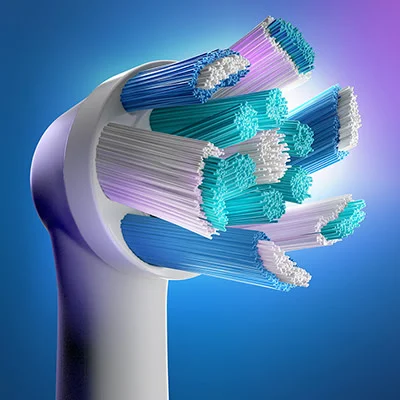 Close-up of an electric toothbrush head with white, blue, teal, and purple bristles against a blue and purple background.