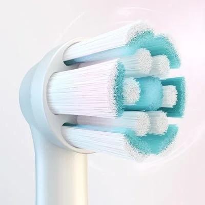 A close-up of a round electric toothbrush head with white and blue bristles.