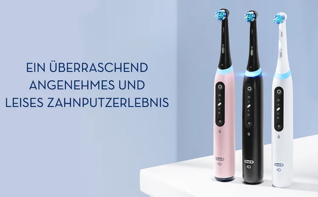 Three electric toothbrushes in pink, black, and white stand on a white surface with the text EIN ÜBERRASCHEND ANGENEHMES UND LEISES ZAHNPUTZERLEBNIS.
