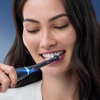 Frau putzt sich mit der elektrischen Oral-B Zahnbürste die Zähne und zeigt so die Anwendung des Produkts.