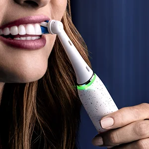 Oral-B Zahnbürste im Einsatz, die Zähne einer Frau reinigend und ein sauberes, strahlendes Lächeln zeigend.