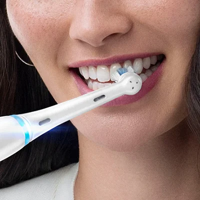 Oral-B iO elektrische Zahnbürste im Einsatz, die Zähne einer lächelnden Frau reinigend.
