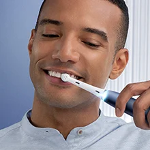Oral-B Zahnbürste in Benutzung, die Zähne eines lächelnden Mannes putzend.