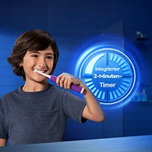 A young boy smiles while brushing his teeth with an electric toothbrush, with a graphic next to him showing the text Integrierter 2-Minuten- Timer.