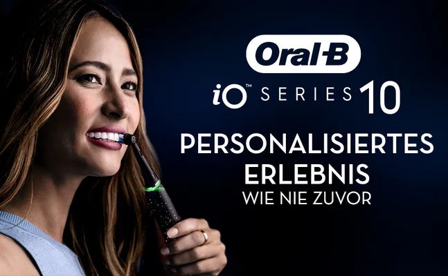 Woman smiling while using an Oral-B iO Series 10 toothbrush: Oral-B iO SERIES 10 PERSONALISIERTES ERLEBNIS WIE NIE ZUVOR.