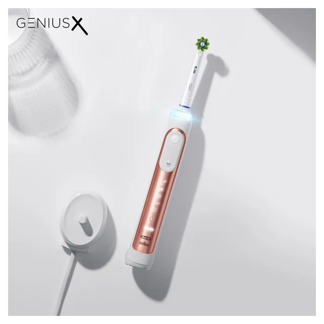 Oral-B Genius X Elektrozahnbürste in Roségold mit Ladestation und beleuchtetem Ring.